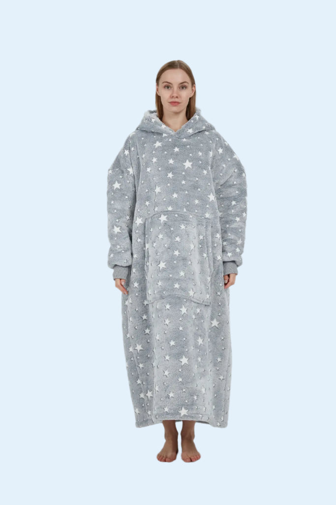  Model smiling with hands in kangaroo pocket of long grey starry hoodie blanket.