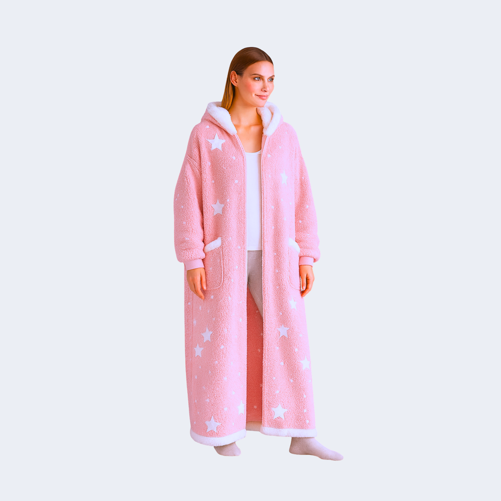 Female model wearing the Starry Elegance Pink Zip Haven hoodie blanket – plush pastel pink fleece with white stars, zip front, and soft sherpa lining on light background.